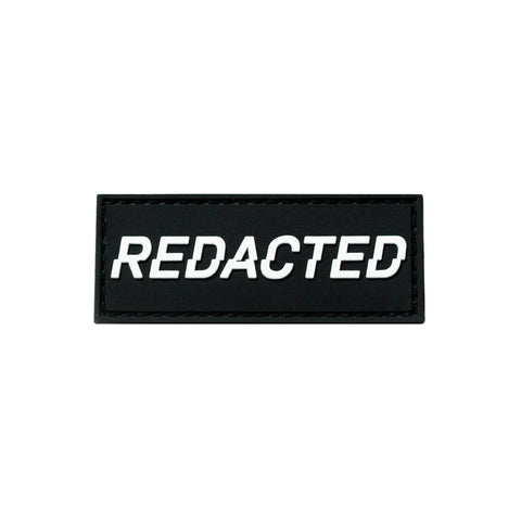 Black and white PVC velcro patch that says REDACTED